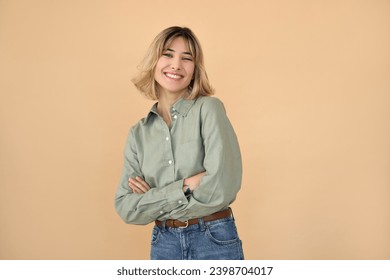 Happy pretty gen z blonde young woman, cute student girl with short blond hair wearing khaki shirt and jeans looking at camera laughing standing arms crossed isolated on beige background. Portrait. - Powered by Shutterstock