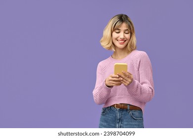 Happy pretty gen z blonde young woman model holding smartphone looking at cell texting message, smiling girl using mobile apps on cell phone standing isolated on purple background with cellphone. - Powered by Shutterstock