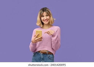 Happy pretty gen z blonde young woman model holding smartphone looking at camera pointing on cell, smiling girl using mobile apps on cell phone standing isolated on purple background with cellphone. - Powered by Shutterstock