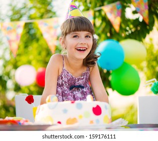 Happy pretty girl with cake at birthday party