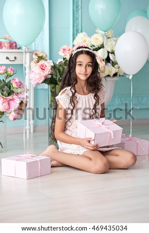 Happy pretty girl with a gift box at birthday party. Happy girl with balloons smiling