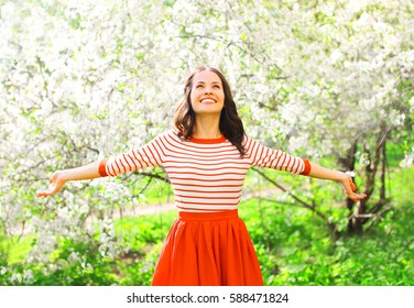 Happy Pretty Smiling Young Woman Enjoying Smell Flowers Over Spring Garden Background