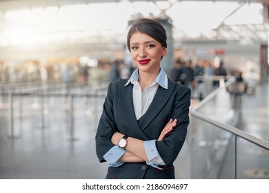 Happy pretty stewardess with arms crossed posing in airport terminal - Powered by Shutterstock