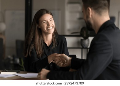 Happy pretty you business professional woman shaking hands with male colleague, smiling, laughing, enjoying teamwork, cooperation. Project managers, business partners giving handshake - Powered by Shutterstock