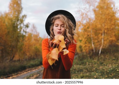 A happy pretty young woman in casual clothes enjoys solitude drinking coffee walking traveling by car in the autumn forest in nature in fall, selective focus