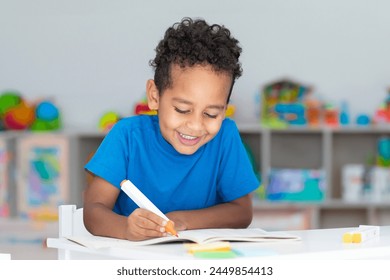 Happy primary school boy drawing with colorful felt pens, sitting at desk in classroom interior, small child doing school homework - Powered by Shutterstock