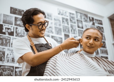 happy professional asian barber held conversation with his male customer while trimming his customer hair - Powered by Shutterstock