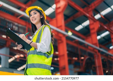 Happy professional beautiful Asian woman industrial engineer,worker,technician with safety hardhat use clipboard to inspect quality control of metal sheet in production steel manufacture factory plant - Powered by Shutterstock