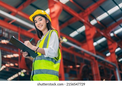 Happy Professional Beautiful Asian Woman Industrial Engineer,worker,technician With Safety Hardhat Use Clipboard To Inspect Quality Control Of Metal Sheet In Production Steel Manufacture Factory Plant