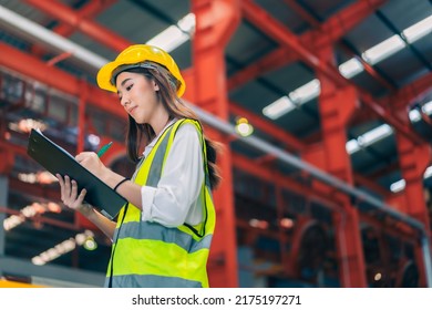 Happy professional beautiful Asian woman industrial engineer,worker,technician with safety hardhat use clipboard to inspect quality control of metal sheet in production steel manufacture factory plant - Powered by Shutterstock