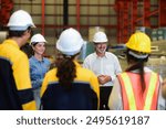 Happy professional Caucasian senior engineer is training industry worker, machine operator, mechanical engineering team in heavy industrial manufacture factory Before starting work in the morning.