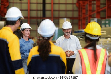 Happy professional Caucasian senior engineer is training industry worker, machine operator, mechanical engineering team in heavy industrial manufacture factory Before starting work in the morning.