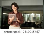 Happy professional female company executive, smiling Hispanic business woman entrepreneur, businesswoman corporate leader manager standing in office looking at camera using tablet. Portrait.