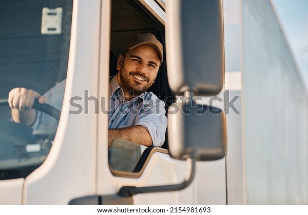 Happy professional truck driver driving his\
truck and looking at camera. Copy\
space.