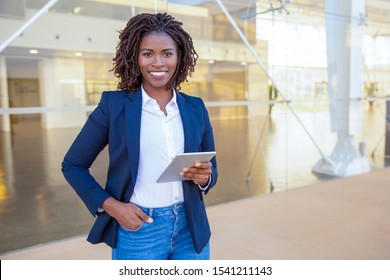 Happy Professional Using Tablet Near Office Building. Young African American Business Woman Standing Outside, Holding Digital Device, Looking At Camera, Smiling. Wi-Fi Concept