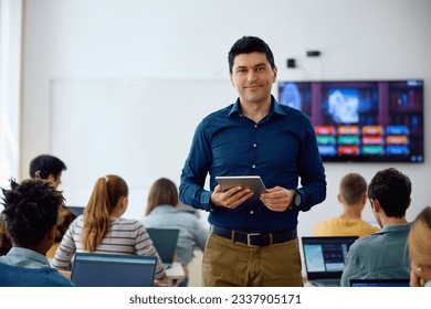 Happy professor with touchpad during computer class at high school looking at camera. - Powered by Shutterstock