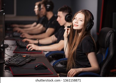 Happy Progamer Girl wearing headset on her long blonde hair looking at camera while participating in online cyber Games Tournament in Internet Cafe