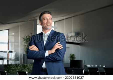 Happy proud mid aged mature professional business man ceo executive wearing suit standing in office arms crossed looking away thinking of success, leadership, corporate growth concept.