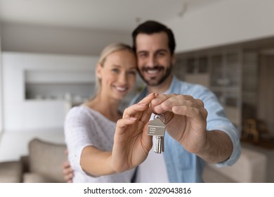 Happy Proud Millennial Couple Holding, Showing Keys, Smiling At Camera. Husband And Wife, New Homeowners, Tenants Excited With Buying House, Real Estate Property Purchase, Renting Apartment. Close Up