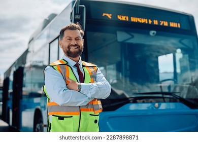 Happy public transport driver with crossed arms in front of a bus looking at camera. Copy space.
