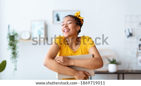 Happy With Purchase. Portrait of smiling african american female buyer hugging carton cardboard box with present, received good parcel, satisfied with gift, lady embracing package at home