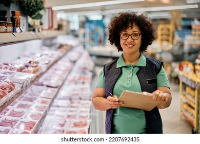 Happy quality control manager working in supermarket and looking at camera. - Powered by Shutterstock