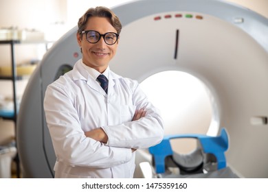 Happy Radiology Technologist Posing In Scanner Room At Medical Center