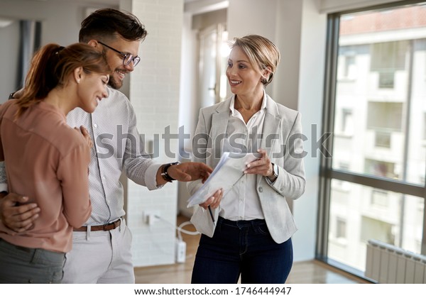 Happy Real Estate Agent Showing Couple Stock Photo (Edit Now) 1746444947
