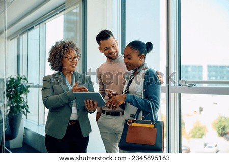 Happy real estate agent using digital tablet with her clients during consultations in the office. Copy space.