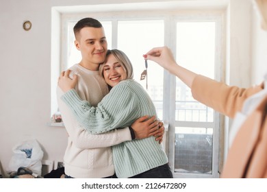 Happy Real State Agent Giving New House Key To A Young Couple. Couple Taking Keys With House Keychain. Couple Receiving House Key From Real Estate Agent.