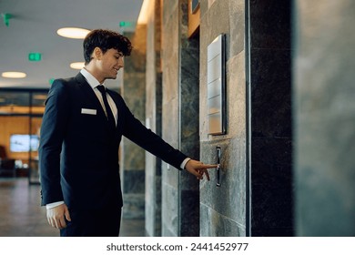 Happy receptionist waiting for elevator in hotel lobby. Copy space.  - Powered by Shutterstock