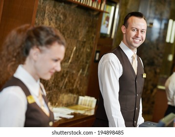 Happy receptionist worker standing at hotel counter