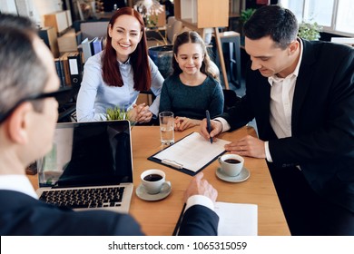 Happy red-haired mother with little daughter is looking at lawyer while father signs documents. Family in office of family lawyer.