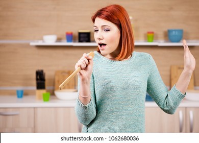 Happy Redhead Woman In The Kitchen Singing