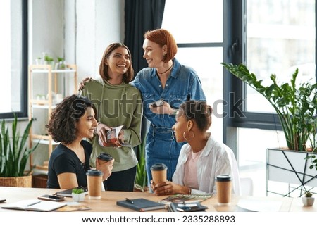 happy redhead woman with smartphone embracing young female friend near multiethnic women drinking coffee to go during conversation n interest club, solidarity and understanding concept Foto stock © 