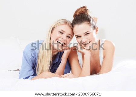 Happy, relax and portrait of women in bed laughing together as happiness isolated in a studio white background. Smile, funny and female friends laugh at a joke and feeling excited in a bedroom