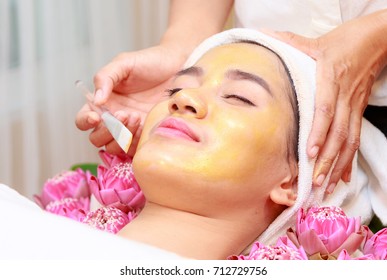 Happy Relax Woman Getting Gold Facial Mask At Beauty Salon.