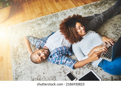 Happy, Relaxed And Carefree Couple Bonding Together On The Living Room Floor At Home. Loving, Affectionate And Smiling Boyfriend And Girlfriend Relaxing, Typing On A Laptop And Lying Down From Above