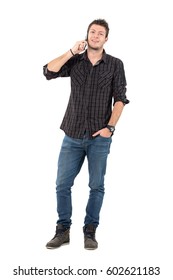 Happy Relaxed Casual Man Talking On The Mobile Phone Looking At Camera.  Full Body Length Portrait Over White Studio Background.