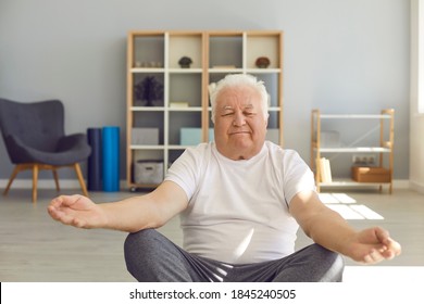 Happy Relaxed Chubby Mature Man Practising Easy Or Lotus Yoga Pose, Meditating And Doing Hatha Breathing Exercise At Home Or In Geriatric Wellness Center. Senior People Leading Active Life Concept