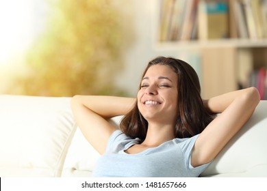 Happy relaxed girl resting sitting on a couch in the living room at home