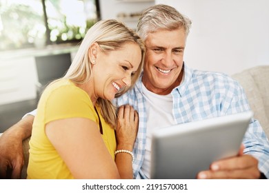 Happy, Relaxed And In Love Mature Couple Watching A Movie Together On A Tablet Online While Relaxing On A Couch Indoors At Home. Smiling Senior Man And Woman Streaming Their Entertainment Tv Series