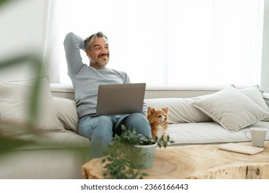 Happy relaxed Middle aged Caucasian man relaxing sitting on couch with his chihuahua dog lying besides are looking at something together. Mature Adult man working laptop at home. Pet friendly Concept - Powered by Shutterstock