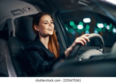 a happy, relaxed woman enjoys a night drive while sitting in a car