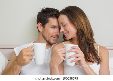 Happy Relaxed Young Couple With Coffee Cups At Home