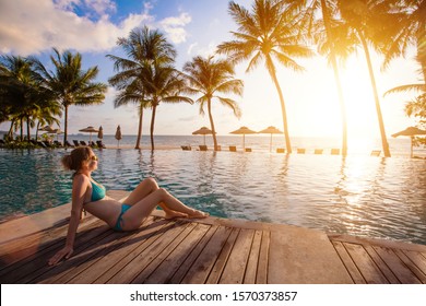 Schöne, entspannende Frau in der Nähe des Swimmingpools mit Blick auf das Meer und Kokospalmen. Luxushotel mit Liegestühlen. Urlaub reisen in tropische exotische Insel Land.