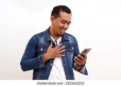 Happy Relieved Asian Man Standing While Holding A Cell Phone. Isolated On White Background