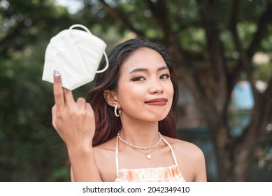 A happy and relieved Filipino woman holds her recently removed KN-95 face mask. Covid-free scenario. - Powered by Shutterstock