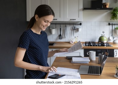 Happy Renter Girl Doing Domestic Paperwork At Home, Reviewing Bills, Documents, Counting Mortgage, Rent, Tax Fees On Calculator, Calculating Money, Finance At Table With Laptop