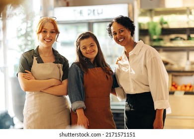 Happy Retail Workers Smiling At The Camera While Standing Together In A Grocery Store. Group Of Three Diverse Women Working Together In A Successful Small Business.